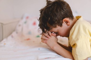 Elleri bağlı bir çocuk, dua ediyor ya da meditasyon yapıyor. Hıristiyanlık, din ve inanç kavramı.