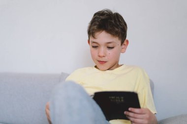 Bir çocuk kutsal kitabı okuyor ve dua ediyor ya da meditasyon yapıyor. Hıristiyanlık, din ve inanç kavramı.