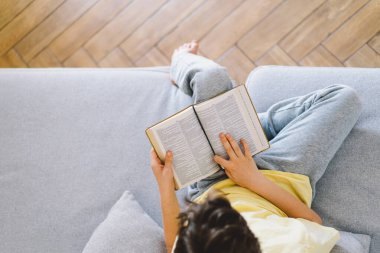 Bir çocuk kutsal kitabı okuyor ve dua ediyor ya da meditasyon yapıyor. Hıristiyanlık, din ve inanç kavramı.