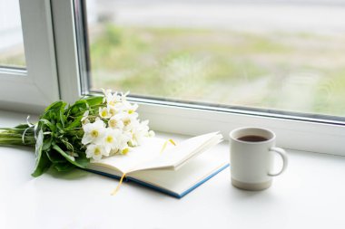 Pencere kenarında güzel bir yaz, sakin bir hayat. Bir buket beyaz çiçek Helleborus ve sıcak bir evin pencere eşiğinde bir kitap..