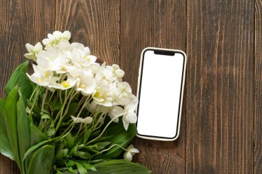 Cep telefonu ve bahardaki beyaz çiçek Helleborus ahşap arka planda. Aşk teması, anneler günü ya da kadınlar günü. Stil tebrik kartı
