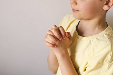 Elleri bağlı bir çocuk, dua ediyor ya da meditasyon yapıyor. Hıristiyanlık, din ve inanç kavramı.