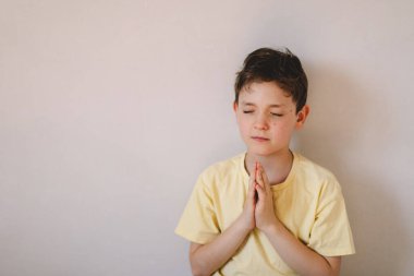Elleri bağlı bir çocuk, dua ediyor ya da meditasyon yapıyor. Hıristiyanlık, din ve inanç kavramı.