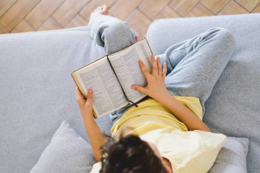 Kanepede kitap okuyan sevimli çocuk. Ev Okulu ve Eğitim Konsepti