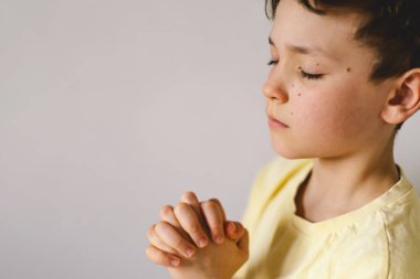 Elleri bağlı bir çocuk, dua ediyor ya da meditasyon yapıyor. Hıristiyanlık, din ve inanç kavramı.