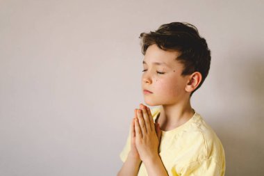 Elleri bağlı bir çocuk, dua ediyor ya da meditasyon yapıyor. Hıristiyanlık, din ve inanç kavramı.