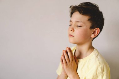 Elleri bağlı bir çocuk, dua ediyor ya da meditasyon yapıyor. Hıristiyanlık, din ve inanç kavramı.