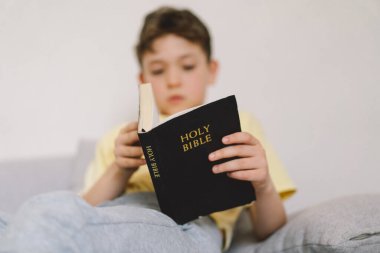 Bir çocuk kutsal kitabı okuyor ve dua ediyor ya da meditasyon yapıyor. Hıristiyanlık, din ve inanç kavramı.