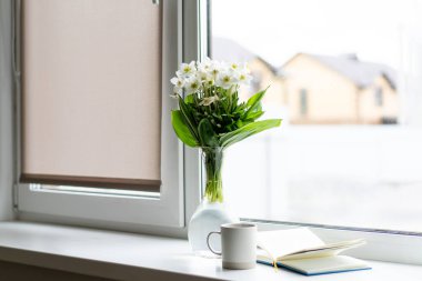 Pencere kenarında güzel bir yaz, sakin bir hayat. Bir buket beyaz çiçek Helleborus ve sıcak bir evin pencere eşiğinde bir kitap..