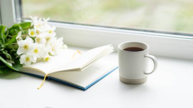 Pencere kenarında güzel bir yaz, sakin bir hayat. Bir buket beyaz çiçek Helleborus ve sıcak bir evin pencere eşiğinde bir kitap..