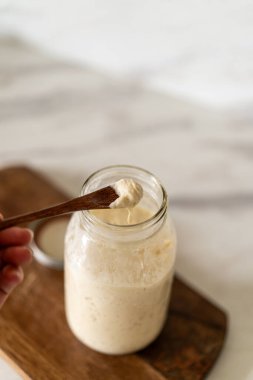 Taze hazırlanmış mayalı ekmek hamuru, aktif bir başlangıç kabı ve karıştırma kabının yanındaki parşömenin üzerinde duruyor..