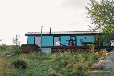 Büyüleyici mavi bir kulübe yemyeşil bir yeşilliğin ortasında duruyor, içinde jakuzi ve açık hava koltukları var. Akşam ışığı bu sakin inzivaya sıcak bir parıltı salıyor..