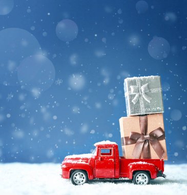 Karlı bir Noel arkaplanı ve hediye kutulu kırmızı bir araba. - Mutlu Noeller ve yeni yılınız kutlu olsun.