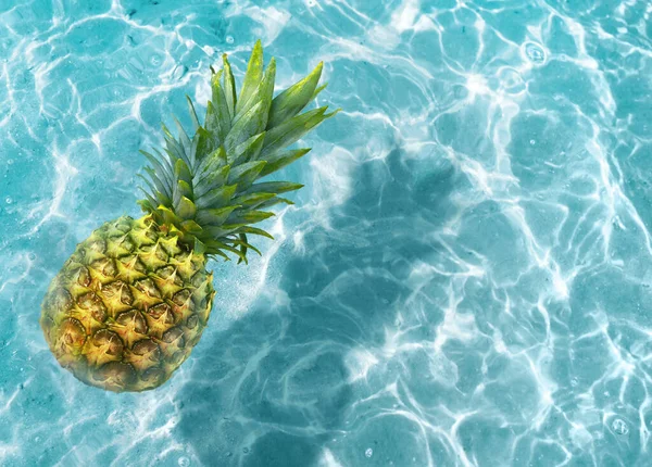 Yellow pineapple on a blue water background. Exotic concept.