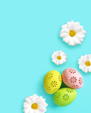 Easter holiday background with colorful easter eggs and white flowers on blue background. Top view from above