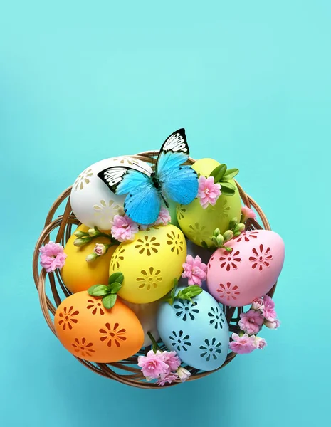 Multi colors Easter eggs in the basket and flowers on blue background. Pastel color Easter eggs