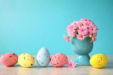 Mavi bir zemin üzerinde çiçekler ve paskalya yumurtaları ve metin için yer var..