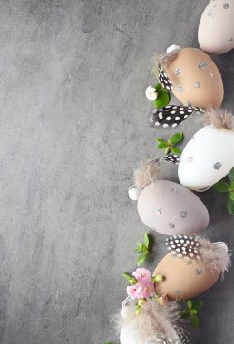 Paskalya kutlaması için gri arka planda çiçeklerle süslü renkli yumurta koleksiyonu. Tatil kavramı.