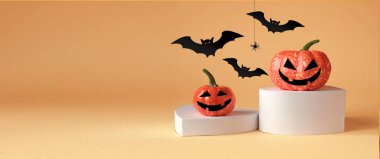 Cadılar Bayramı süsleri, podyumda balkabağı, turuncu arka planda örümcek ve yarasa. Cadılar Bayramı partisi konsepti