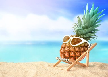 Güneş gözlüklü ananas sahildeki şezlongda dinleniyor. Yaz tropik konsepti.