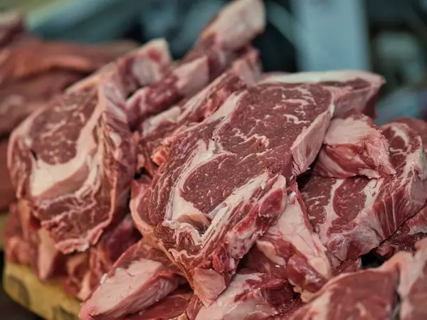 Restoranda seramik tabakta servis edilen çiğ bifteğin yakın plan görüntüsü. Bir şefin eli bıçakla taze eti pişirmeden önce keser. Geleneksel yemek hazırlıklarını doğal ışık ve otantik ortamlarla gösteren gerçekçi yemek fotoğrafçılığı.