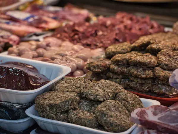 Restoranda seramik tabakta servis edilen çiğ bifteğin yakın plan görüntüsü. Bir şefin eli bıçakla taze eti pişirmeden önce keser. Geleneksel yemek hazırlıklarını doğal ışık ve otantik ortamlarla gösteren gerçekçi yemek fotoğrafçılığı.