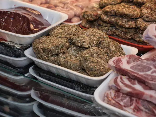 Restoranda seramik tabakta servis edilen çiğ bifteğin yakın plan görüntüsü. Bir şefin eli bıçakla taze eti pişirmeden önce keser. Geleneksel yemek hazırlıklarını doğal ışık ve otantik ortamlarla gösteren gerçekçi yemek fotoğrafçılığı.