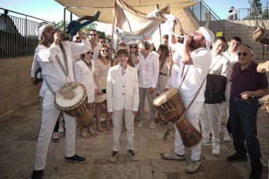 Kudüs 'teki Batı Duvarı yakınında Bar Mitzvah kutlaması. Beyaz giyinmiş bir grup müzisyen ve konuk geleneksel müzik icra ediyorlar. Bu Yahudi ergenlik ayini 13 yaşındaki bir çocuk için ergenlik çağının geldiğini gösteriyor..