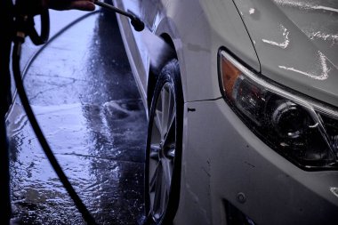 Tamircide araba tekerleğini temizleyen bir tamirci. Araç bakımı devam ediyor. 