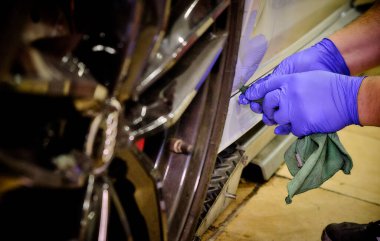 Tamircide araba tekerleğini temizleyen bir tamirci. Araç bakımı devam ediyor. 