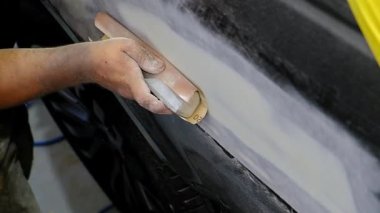 Tamirci, oto tamir atölyesinde bir araba tekerleğini yavaş çekimde temizliyor. Araç bakımı devam ediyor. 
