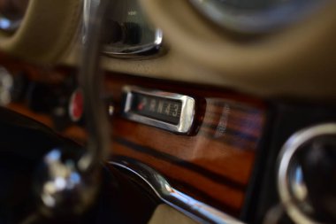 Caddeye güneş ışığı altında park edilmiş klasik kırmızı bir Mercedes Benz 280 SE Coupe. İkonik Alman lüks aracında krom bir ızgara, belirgin yuvarlak farlar ve 1960 'ların klasik tasarım detayları yer almaktadır..