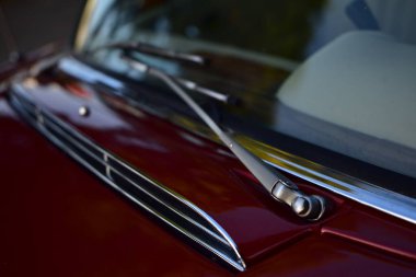 Caddeye güneş ışığı altında park edilmiş klasik kırmızı bir Mercedes Benz 280 SE Coupe. İkonik Alman lüks aracında krom bir ızgara, belirgin yuvarlak farlar ve 1960 'ların klasik tasarım detayları yer almaktadır..