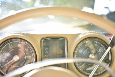 Caddeye güneş ışığı altında park edilmiş klasik kırmızı bir Mercedes Benz 280 SE Coupe. İkonik Alman lüks aracında krom bir ızgara, belirgin yuvarlak farlar ve 1960 'ların klasik tasarım detayları yer almaktadır..