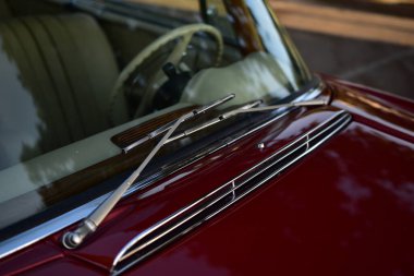 Caddeye güneş ışığı altında park edilmiş klasik kırmızı bir Mercedes Benz 280 SE Coupe. İkonik Alman lüks aracında krom bir ızgara, belirgin yuvarlak farlar ve 1960 'ların klasik tasarım detayları yer almaktadır..