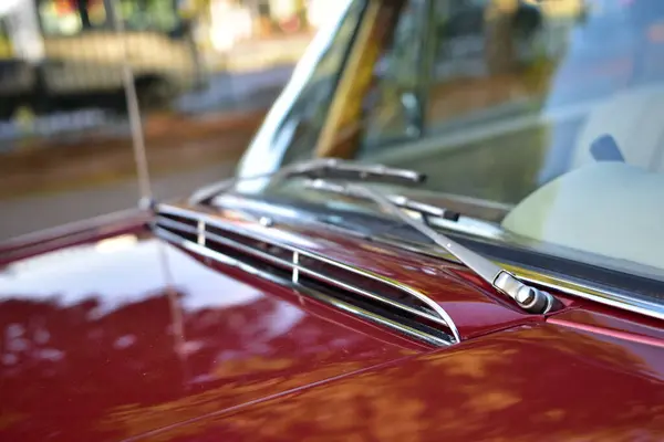 Caddeye güneş ışığı altında park edilmiş klasik kırmızı bir Mercedes Benz 280 SE Coupe. İkonik Alman lüks aracında krom bir ızgara, belirgin yuvarlak farlar ve 1960 'ların klasik tasarım detayları yer almaktadır..