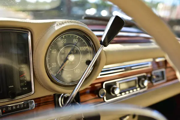 Caddeye güneş ışığı altında park edilmiş klasik kırmızı bir Mercedes Benz 280 SE Coupe. İkonik Alman lüks aracında krom bir ızgara, belirgin yuvarlak farlar ve 1960 'ların klasik tasarım detayları yer almaktadır..