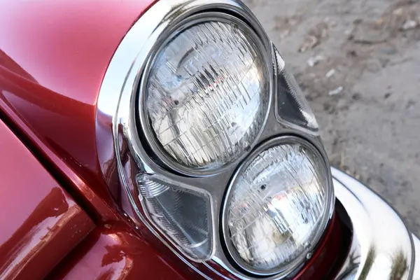 Caddeye güneş ışığı altında park edilmiş klasik kırmızı bir Mercedes Benz 280 SE Coupe. İkonik Alman lüks aracında krom bir ızgara, belirgin yuvarlak farlar ve 1960 'ların klasik tasarım detayları yer almaktadır..