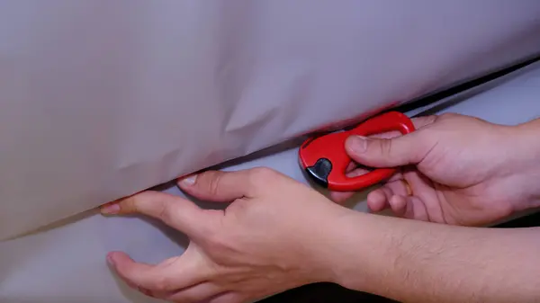 Bir araba servisi atölyesinde özel araba döşemesi için siyah deri ya da sentetik malzeme kesip hazırlamak. Elleri yakın plan işaretleme, makasla kesme, ve malzeme parçalarını şekillendirme.