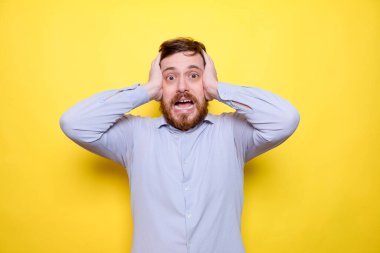 Sarı arka planda duran korkmuş genç adam şok oldu.