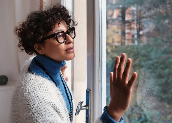 Sad black woman at home looking out of the window