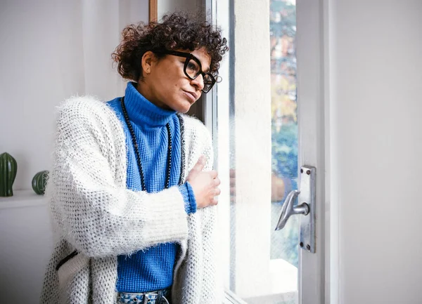 Sad black woman at home looking out of the window