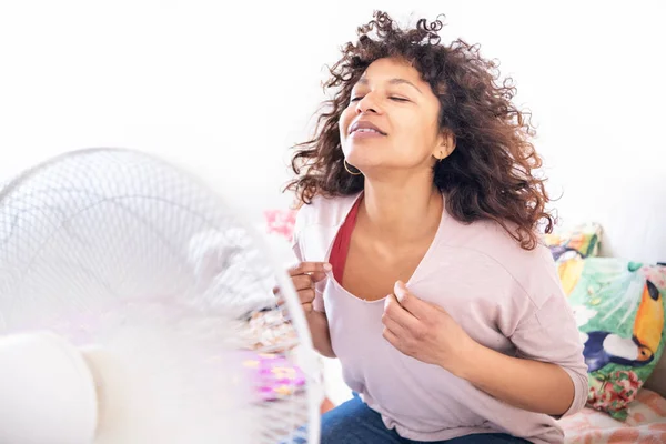Black woman exhausted from summer heat while standing in front of fan