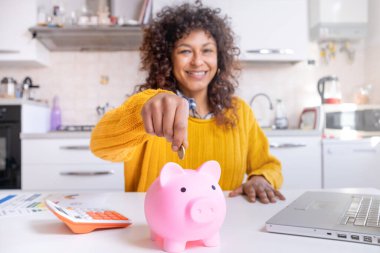 Smiling black woman saving goal for future retirement plan, focus on piggy bank