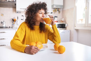 Happy black woman drinking healthy extract orange juice