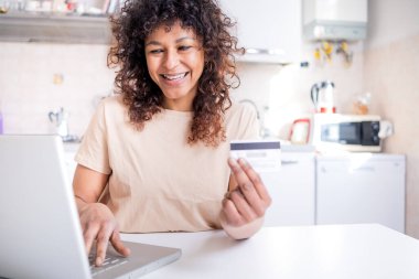 Happy black woman using credit card and home shopping online