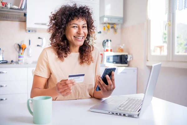 Smiling black woman holding credit card during online shopping