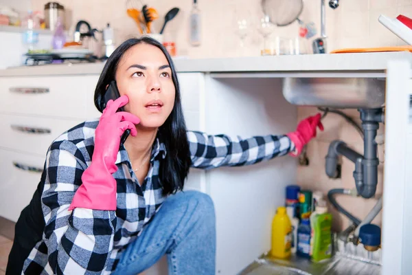 Stressed housewife calling a plumber service for assistance after water leak problem at home