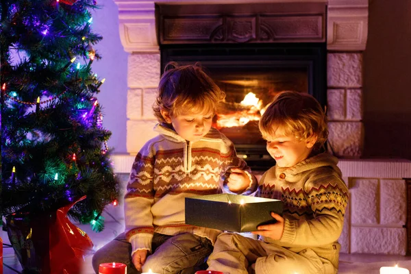 Noel Zamanında Bir Şöminenin Evde Oturan Iki Küçük Çocuk Mutlu — Stok fotoğraf