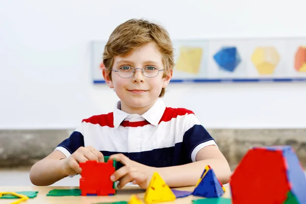 小男孩 戴着眼镜 在学校或幼儿园里玩色彩艳丽的塑料元件套件 快乐的孩子建设和创造几何图形 学习数学和几何 — 图库照片